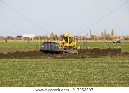 The Yellow Tractor With Attached Grederom Makes Ground Leveling.