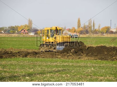 The Yellow Tractor With Attached Grederom Makes Ground Leveling.