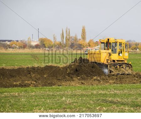 The Yellow Tractor With Attached Grederom Makes Ground Leveling.