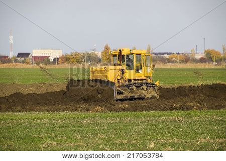 The Yellow Tractor With Attached Grederom Makes Ground Leveling.