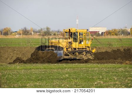 The Yellow Tractor With Attached Grederom Makes Ground Leveling.