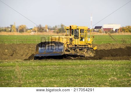 The Yellow Tractor With Attached Grederom Makes Ground Leveling. Work On The Drainage System In The 