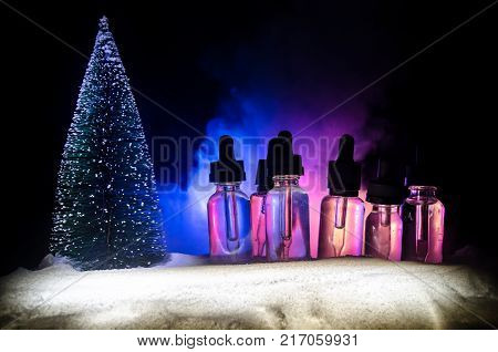 Electronic Cigarette With Vape Liquids And Christmas Decorations On Bokeh Lights Background
