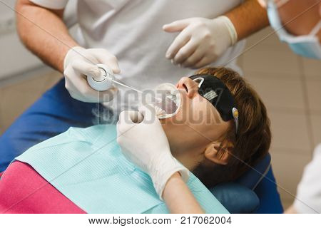 Close Up Process Of Preparing And Installing Dental Ceramic Crown. Male Professional Dentist Helps T