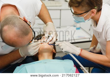 Close Up Process Of Preparing And Installing Dental Ceramic Crown. Male Professional Dentist Helps T