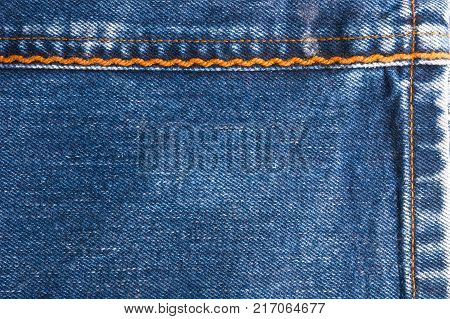 Blue faded jeans texture with yellow seams, macro, close up