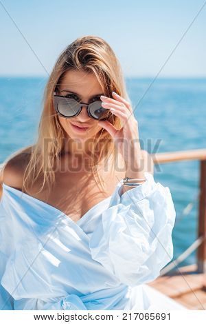 beautiful woman in a white blouse by the sea on a beach bed