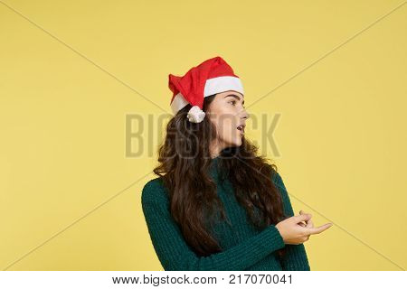 woman points to free space for copy, light yellow background, winter, new year.