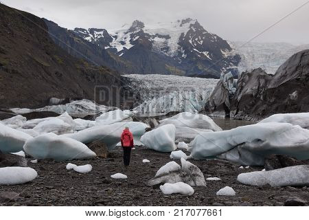 Adventure woman by glacier nature on Iceland. Tourist by glacial lagoon / lake of Fjallsarlon Vatna glacier Vatnajokull National Park. Young woman visiting nature landscape.