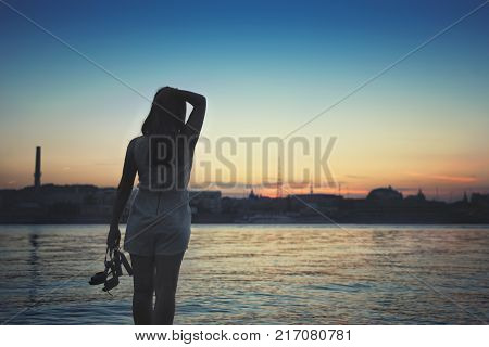 girl standing on the beach watching the sunset