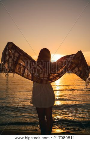 girl standing on the beach watching the sunset