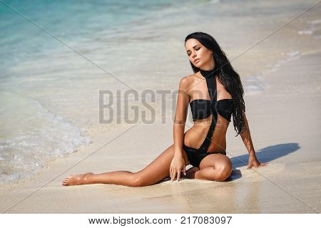 Beautiful young girl in a sexy black swimsuit in paradise islands