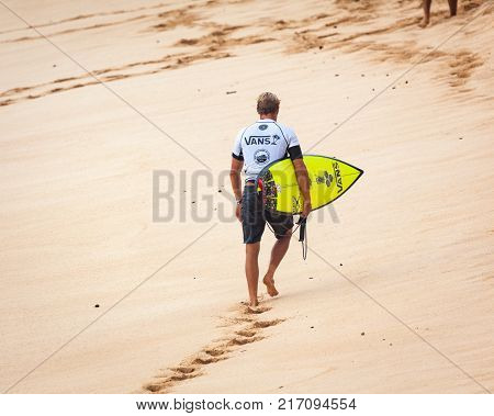 SUNSET BEACH HAWAII USA - DECEMBER 2, 2017: Competitive surfer with surfboard walking on beach at the 2017 Vans World Cup of Surfing competition at Sunset Beach on Oahu's scenic North Shore. This is the second of three surfing competitions and Conner Coff