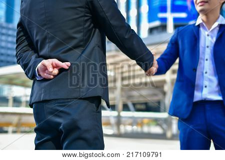 Business concept hypocrisy Young businessmen shake hands with fraudulent models.