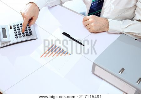 businessman is working with a calculator on desk