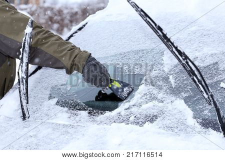 hand is cleaning a wind screen of a car