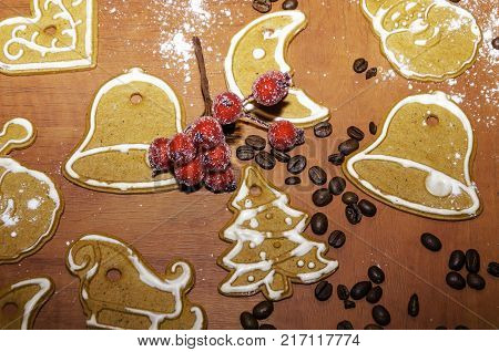Christmas gingerbreads with white frosting, coffee beans and a rowan twig for decoration on a wooden board