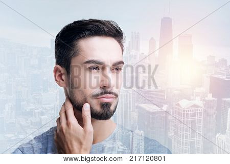 Positive thoughts. Kind young romantic man feeling emotional while looking into the distance and remembering sweet gentle touch of his beloved woman