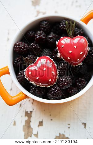 A full blackboy plate with a dessert in the form of a heart stands on a wooden background, close-up.