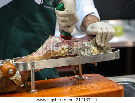Men cutting slices of cured iberian ham