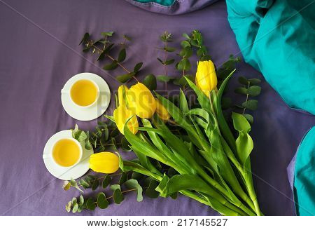 Yellow tulips and two cups of tea in bed, morning