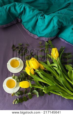 Yellow tulips and two cups of tea in bed, morning