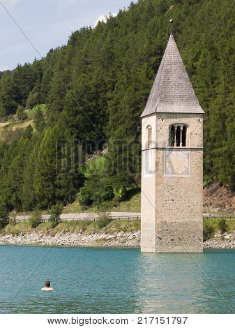 Submerged Tower Of Reschensee Church, Man Swimming Next To It