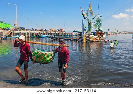 Jembrana Bali Island Indonesia - September 20 2015: A way of life earning money in Bali. In Perancak village harbour Indonesian dockers unload traditional fishing boat for shipping fish to cannery