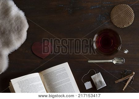 beautiful cozily flat lay of cup of tea book sheepskin cookie and spices on rustic wooden ground