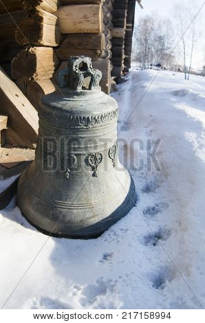 A large iron bell removed from the main tower standing in the snow.
