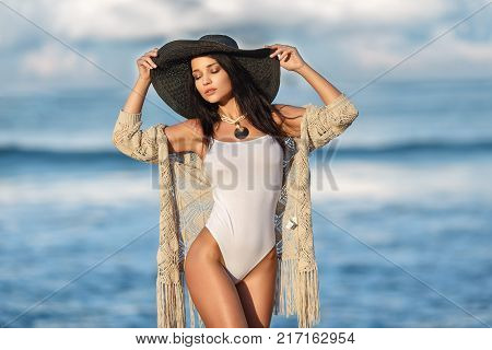 Beautiful young girl in a sexy white swimsuit on the beach