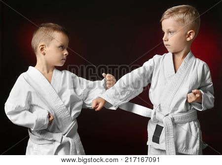 Little children practicing karate on dark background