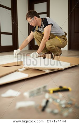 Carpenter man assembling furniture in house. Assemble furniture theme