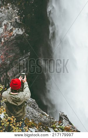 Man taking photo of Vettisfossen waterfall by smartphone adventure lifestyle concept vacations outdoor wanderlust