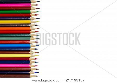 Color pencils in a row on the left side of the photo. Very sharpened pencils. Different colors. Dark light red pink green brown yellow red blue blue. Isolated photo white background.