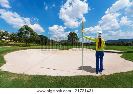 green of a beautiful golf course surrounded with bunkers with dramatic summer sky
