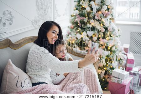 Well-groomed hand of a woman holding a phone taking a selfie with her daughter, little girl.
