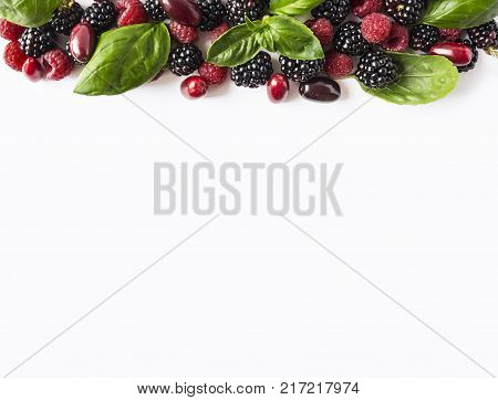 Black and red berries isolated on white. Ripe blackberries raspberries cornels and basil leaves on white background. Berries with copy space for text. Top view.