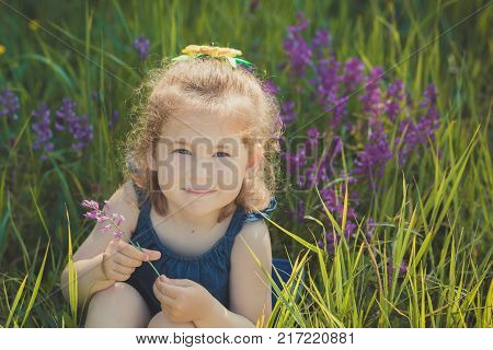 Cute Blond Young Girl Child Stylish Dressed In Blue Jeans Dress Posing On Meadow Of Forest Wild Mayw