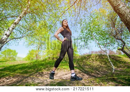Tightrope walker is on a tight sling which is fixed on the trees at a low altitude. Slasklining extreme sport a balancing act.