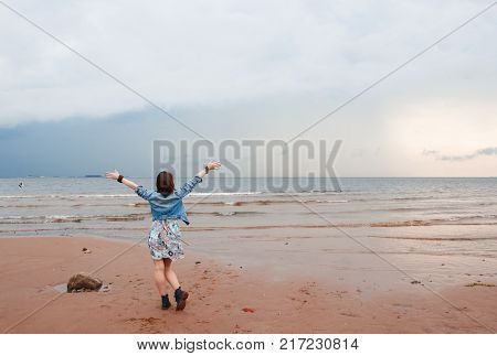 Young hippie woman at the beach looking at a storm coming. Near stones