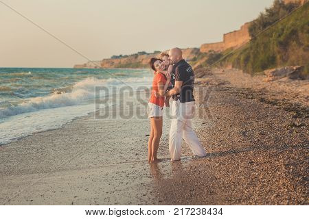 Family Together Enjoying Summer Vacation Time On Sandy Beach On Amazing Scene Of Sea Cliff And Sky W