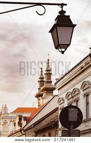Historical center Gheorghe Lazar Street with its ancient houses in Timisoara at sunset, Romania. Lantern on an iron pillar against a cloudy sky. Soft focus
