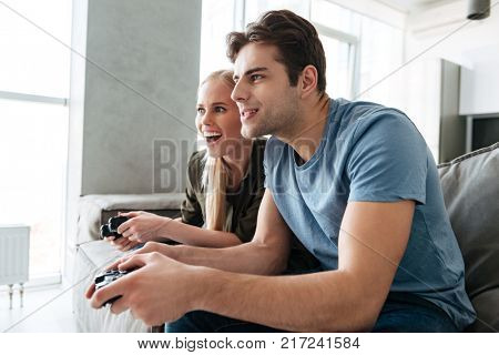 Focused lady and concentarted happy man playing video games at home in living room