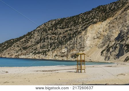 famous beach of Myrtos in Kefalonia with the mountains that plummet and lifeguard box to help fight the strong waves that turn the calcareous stones into dust