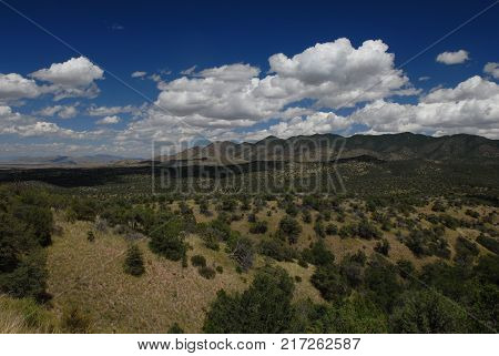 A landscape showing the foothills scrubland and sky with white puffy clouds.