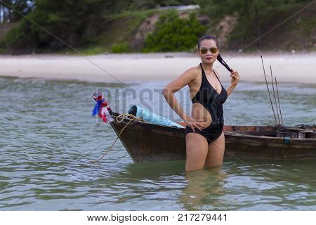 Woman black bikini relax with small boat on beach at Ban Krut Beach Prachuap Khirikhan Province Thailand