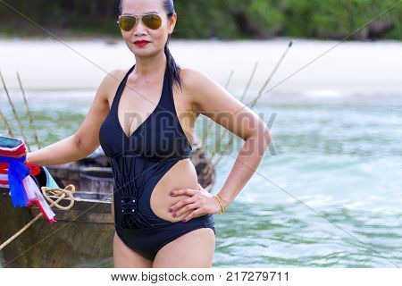 Woman beautiful black bikini with small boat on beach at Ban Krut Beach Prachuap Khirikhan Province Thailand