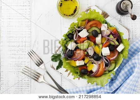 Greek salad in a ceramic plate on a white wooden background. Traditional Greek dish. Selective focus.Top view.