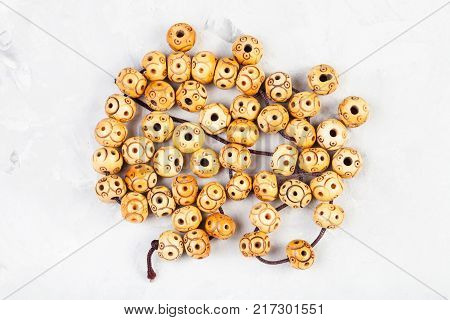 string of beads carved from natural bone on gray concrete background